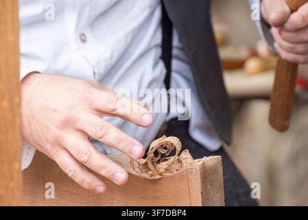 Nahaufnahme von Handwerkern, die traditionelle Holzbearbeitungswerkzeuge vor einem Steinmauerhintergrund verwenden Stockfoto
