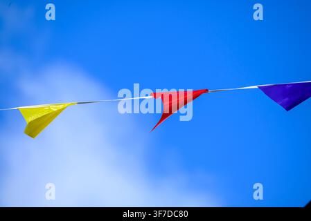 Festliche Wimpelgirlande vor klarem blauem Himmel, die einen hellen Partyhintergrund bildet Stockfoto