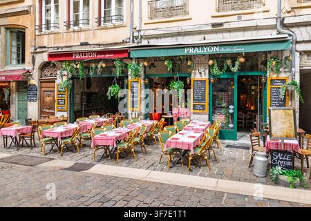 Lyon, Frankreich - 27. Juli 2026: Außenterrasse des Restaurants Pralyon Bouchon Lyonnais mit rot karierten Tischen auf einer Kopfsteinpflasterstraße in der Altstadt Vieux Stockfoto