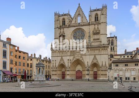 Lyon, Frankreich - 27. Juli 2026: Fassade der Saint-Jean-Kathedrale und Brunnen auf dem Place Saint-Jean im Vieux Lyon unter blauem Himmel. Stockfoto