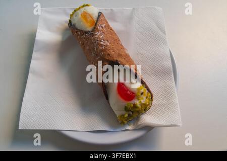 Ein einzelnes traditionelles sizilianisches Cannoli-Dessert, gefüllt mit süßer Ricotta-Creme, auf einem Tisch, authentisches italienisches Gebäck Stockfoto