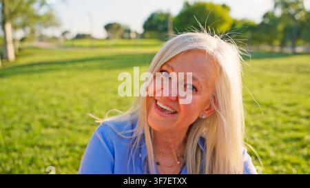 Seniorin lächelt im Freien und genießt das Licht der goldenen Stunde Stockfoto