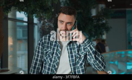 Positiver glücklicher kaukasischer Geschäftsmann, der einen Mobiltelefonanruf mit einem Kunden/Käufer führt, lächelnd sorglos in einem Einkaufszentrum, Firma, Mann, Geschäftsmann, Gespräch Stockfoto