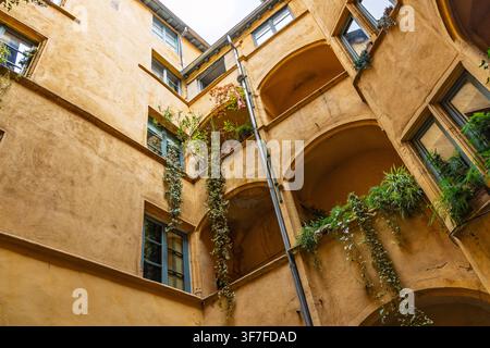 Lyon, Frankreich: Historischer Innenhof einer traditionellen Renaissance-Traboule mit gelben Wänden und Balkonen in der Altstadt von Vieux Lyon. Stockfoto