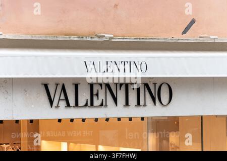 ITALIEN, VENEDIG, 11. JULI 2025: Eine Nahaufnahme zeigt die Fassade des Valentino-Geschäfts mit einem weißen Markisen und großen schwarzen Markenbuchstaben über dem Fenster. Stockfoto