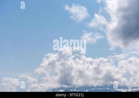 Gleitschirmflieger fliegt über die Alpe di Siusi mit Kumuluswolken und blauem Himmel Stockfoto