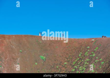 Touristen wandern am Rand eines Vulkankraters vor einem klaren blauen Himmel, Mount Etna, Sizilien Stockfoto
