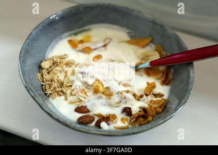 Müslischale mit cremigem Joghurt, Haferflocken, Cornflakes, Mandeln, Trockenfrüchten und Bananenscheiben, die eine nahrhafte und ausgewogene Mahlzeitoption bieten Stockfoto