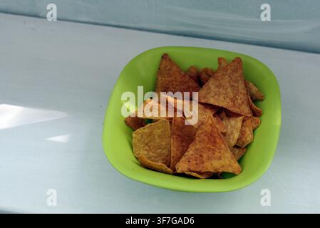Tortilla-Chips, die eine hellgrüne Schüssel füllen, bieten eine knusprige und herzhafte Snack-Option, bereit zum Dippen oder als Vorspeise serviert Stockfoto