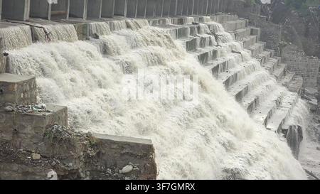 Nahaufnahme von Wasser, das über einen Steindamm stürzt, mit herabstürzenden Wasserfällen Stockfoto