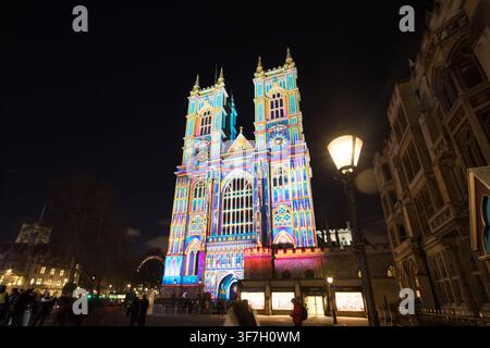 Westminster Abbey in London wird von einer atemberaubenden, farbenfrohen Lichtprojektionsshow beleuchtet, die die festliche Jahreszeit in der Nacht feiert. Stockfoto