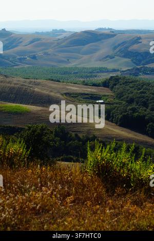 Atemberaubende italienische Landschaft mit geschichteten Bergen und grünen Tälern unter einem dunstigen Himmel in der Toskana. Stockfoto