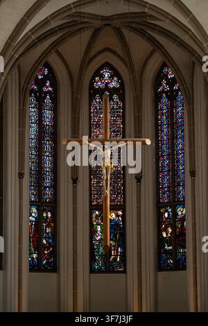 Kruzifix in einer historischen gotischen Kirche. Kruzifix unter bunten Buntglasfenstern. Heiliges christliches Kruzifix mit Jesus Christus. Kirche Stockfoto
