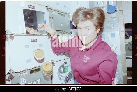 James Voss, ein amerikanischer Astronaut, auf dem Mitteldeck mit einem Erdnussbutterglas während der STS-094-Mission des Space-Shuttle-Programms. Stockfoto
