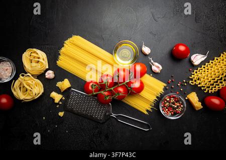Hintergrund Pasta. Verschiedene Arten von trockener Pasta mit Gemüse und Kräutern auf schwarzem Hintergrund. Freier Platz für Text. Draufsicht Stockfoto
