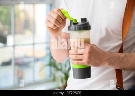 Mann öffnet eine Protein-Shaker-Flasche mit einem gesunden Getränk, Fitness- und Ernährungskonzept, Erholung nach dem Training Stockfoto