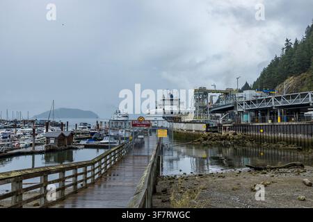 Horseshoe Bay, Kanada – 27. Juli 2026: Ein nasser Holzsteg führt an einem Sewell's Marina East Moorage-Schild vorbei in Richtung des BC-Fährterminals in Horseshoe Bay Stockfoto