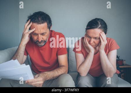 Besorgtes Paar mittleren Alters, das zu Hause Rechnungen und Dokumente durchsieht, finanzieller Stress, Schulden und Haushaltsbudget-Probleme als Konzept, selektive Fokussierung Stockfoto