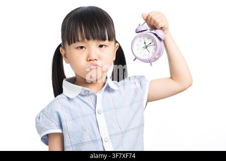 Frustriertes Kind hält einen Wecker, der Zeitmanagementdruck zeigt Stockfoto