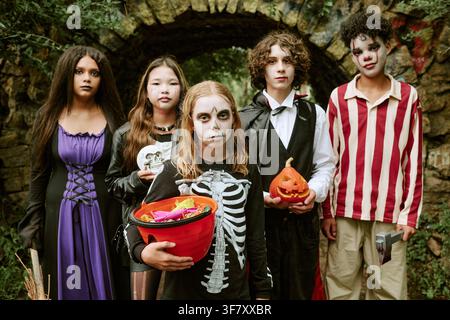 Porträt von vielfältigen Kindern in Halloween-Kostümen, die Leckereien halten Stockfoto