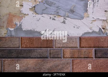 Unfertige Reparatur an der Verlegung von Fliesen an der Wand, gefrorenes Bauprojekt Stockfoto