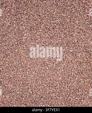 Dies zeigt eine obere Ansicht einer Oberfläche, die mit feinem rotem Granit-Schotter und dekorativem Kies bedeckt ist. Die Textur ist nahtlos und gleichmäßig, geeignet für Stockfoto