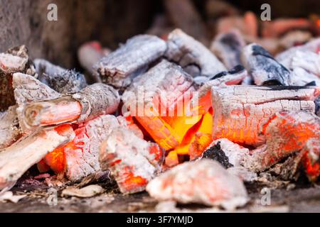 Glühende Glut und heiße Kohlen eines brennenden Holzfeuers im Nahaufnahme mit Asche und Holzkohle Stockfoto