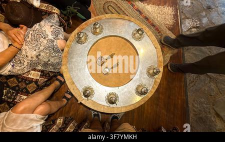 Eine hochwertige Top-Down-Aufnahme aus 90 Grad Blickwinkel von traditionellem türkischem Kaffee, der frisch im heißen Sand gebraut wird, wobei reicher Schaum, Kupfertopf und Stockfoto