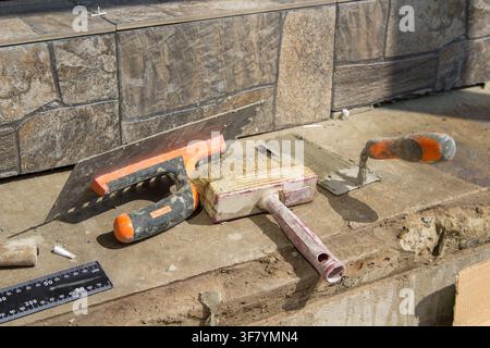 Reparatur der Treppen zum Haus, Werkzeuge auf den Treppen zum keramischen grauen Fliesenstein Stockfoto