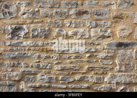 Wand aus horizontal ausgerichteten grauen Steinen, die zusammen mit braunem Zement gehalten werden. Vorderansicht. Stockfoto