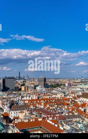 Vertikale Hochwinkelansicht der Wiener Stadtlandschaft mit historischen roten Dächern und moderner Skyline unter blauem Himmel Stockfoto