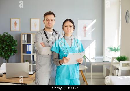 Junger männlicher Arzt in medizinischer Uniform mit einer Krankenschwester, die in die Kamera schaut, in einem Krankenhaus oder einer Klinik Stockfoto