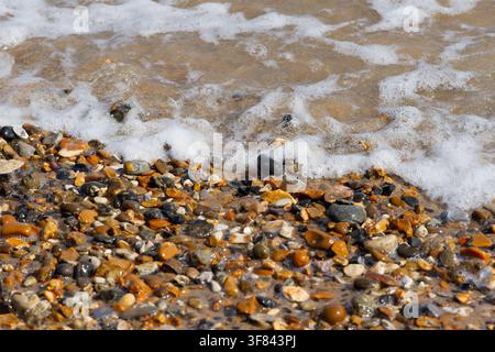 Nahaufnahme von schäumendem Meerwasser und Kieselsteinen an einem Strand Stockfoto