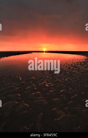 Sonnenunterblick über Walney Island, die sich bei Ebbe an der Küste von Cumbria im Wasser spiegelt Stockfoto