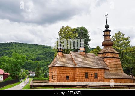 Holzkirche steht in einer ländlichen Gegend Polens mit grüner Landschaft im Hintergrund Stockfoto