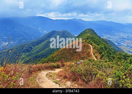 Wanderer gehen auf dem Tai To Yan Ridge Trail in Hongkong, China, mit Bergblick und bewölktem Himmel Stockfoto