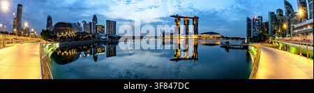 Blick auf Marina Bay in der Dämmerung mit Gebäuden, die sich auf dem Wasser in Singapur spiegeln Stockfoto