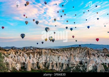 Heißluftballone steigen bei Sonnenaufgang über einzigartigen Felsformationen im Love Valley, Kappadokien, Zentralanatolien, Türkei Stockfoto
