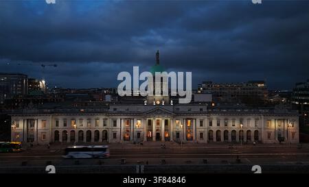 Ansicht des Custom House entlang des Flusses Liffey in der Dämmerung in Dublin, Irland, mit Darstellung architektonischer Details und Stadtleben Stockfoto