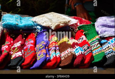 Lebendige gestrickte Socken mit aufwendigen Mustern sind auf einem Tisch auf einem bulgarischen Festival arrangiert, was traditionelle Handwerkskunst und farbenfrohe Muster unterstreicht Stockfoto