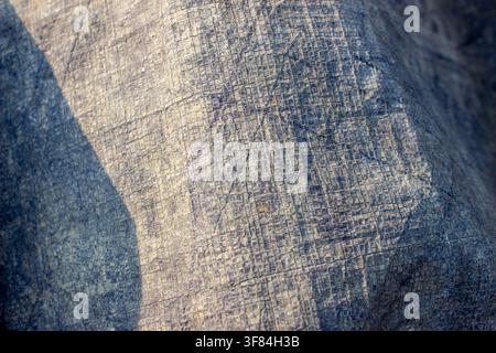 detaillierte Textur einer dunkelgrauen Natursteinwandoberfläche mit künstlerisch geschnitzten Linienstrichen Stockfoto