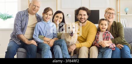 Glückliche multigenerationale Familie mit Labrador-Hund sitzt zusammen auf dem Heimsofa Stockfoto