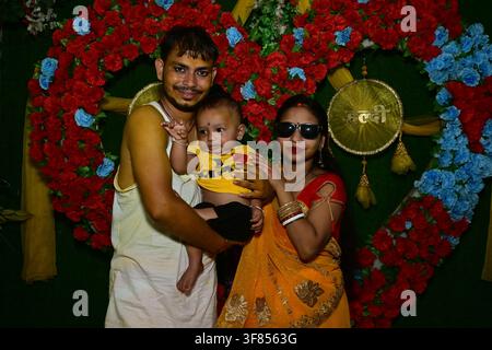 Indische Eltern mit einem Jungen posieren vor einem roten blauen Rosenherz-Hintergrund mit goldenem Beti-Schild während einer Familienfeier und einem traditionellen Event Stockfoto