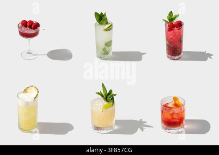 Bunte Sommer-Cocktail-Kollektion mit Obst-Garnierungen und langen Schatten auf weißem Hintergrund Stockfoto