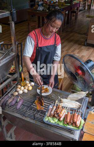 Junge Frau bereitet Essen auf einem Grill in einem Restaurant in Cat Cat, Sapa, Vietnam zu Stockfoto