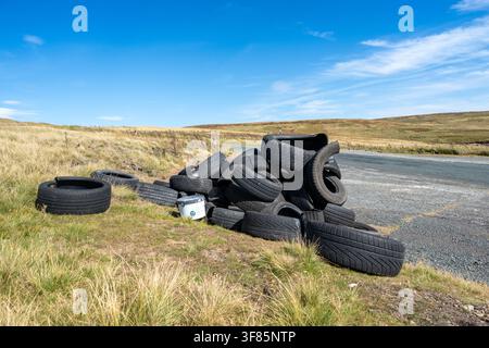 Haufen alter Autoreifen, die an einer ländlichen Straßenseite in den Yorkshire Dales abgeladen wurden und ein Umweltrisiko darstellen. Stockfoto