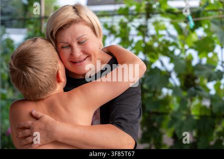 Ein zarter Moment, der in einer Nahaufnahme einer Großmutter eingefangen wurde, die ein Kind in einer warmen Garteneinstellung im Freien umarmt Stockfoto