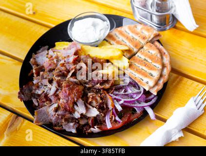 Portion Souvlaki mit gebratener Kartoffel, Zwiebeln, Pitabrot und Sauce Stockfoto