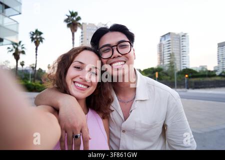 Multirassisches Paar, das ein Selfie macht und die Kamera im Freien lächelnd ansieht. Stockfoto