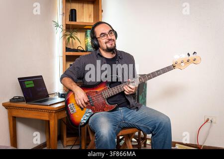 Musiker spielt E-Bassgitarre in einem Heimaufnahmestudio Stockfoto